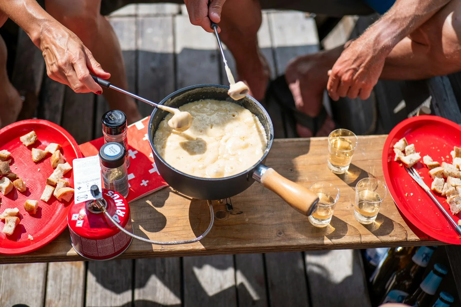 Fondue au fromage dans son caquelon, morceaux de pain piqués sur les fourchettes, sur une table en Suisse